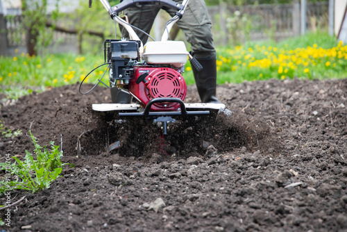 Farmer using tiller on a plowed field
