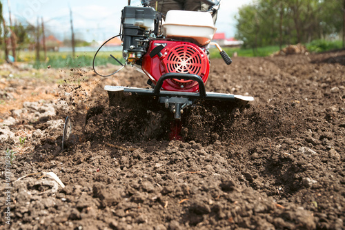Obraz na plátně Farmer using tiller on a plowed field