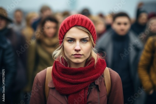 Wallpaper Mural Young woman in red hat and scarf standing with focused expression in a blurry city crowd Torontodigital.ca
