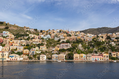 Colorful buildings on a hillside in the idyllic town of Symi by the Aegean Sea on Symi (Simi, Syme) island in Greece on a sunny day.