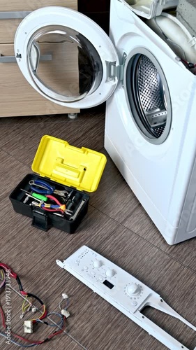 A disassembled washing machine in the kitchen and set of professional tools against the background. Professional repair of household appliances.