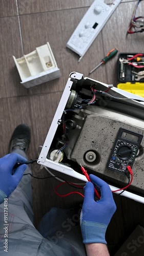Professional washing machine repair. A service engineer tests the integrity of the circuits and the functionality of capacitor.