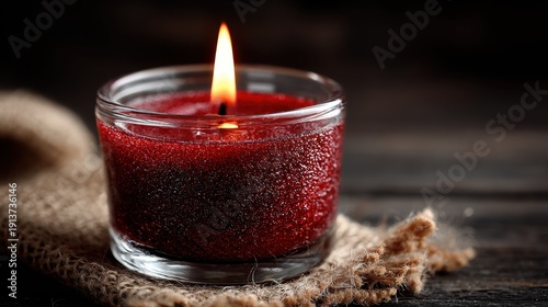 Burning Red Candle in Glass Jar on Burlap Fabric, Dark Rustic Background