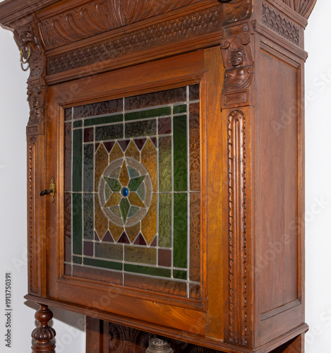 An antique oak buffet cabinet from the Wilhelminian period, circa 1880–1890 features heavily carved wood details and a stained lead-glass door