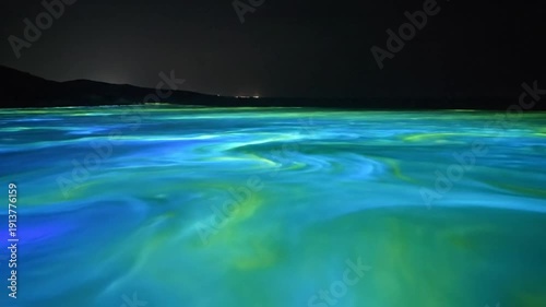 Bio luminescent algae bloom paints a bay at night illuminated by drone perspective