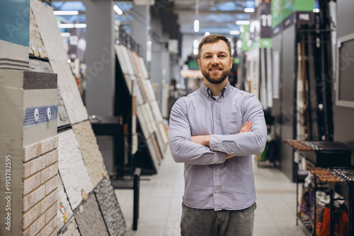 Фотография Smiling man standing with crossed arms in a building materials store showroom, s