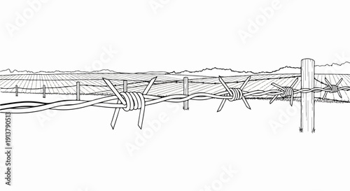 Rustic barbed wire fence in front of a cultivated field under mountains