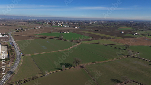 Agricultural Po Valley plain landscape with rural fields and SS10 state road crossing San Nazzaro Piacenza countryside in Emilia Romagna, Italy