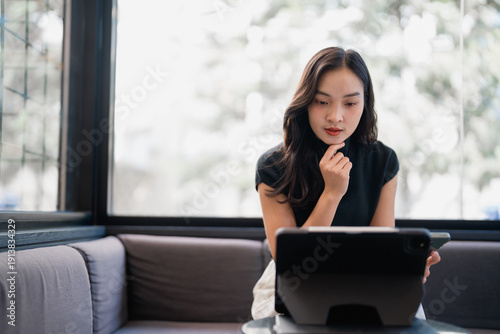 Asian woman thinking while working remotely on digital tablet Free Download Asian woman thinking while working remotely on digital tablet - GFXLoad