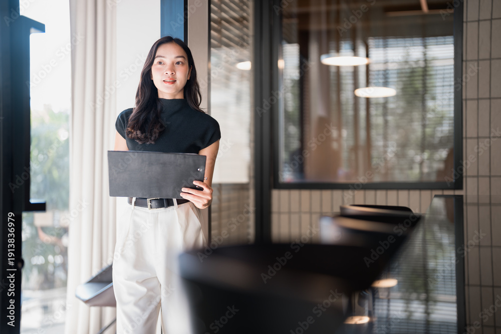 © Tj - Young asian businesswoman holding folder in modern office