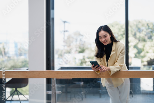 Smiling asian woman receiving good news on smartphone