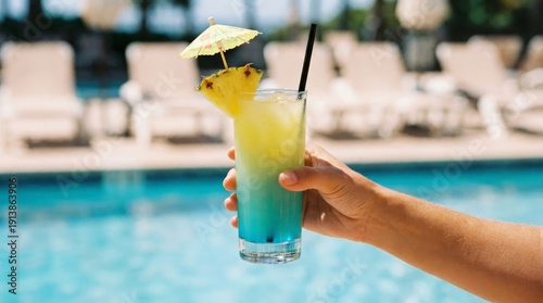 Hand holding a colorful cocktail by the pool, relaxing vacation moment, summer refreshment, leisure time, holiday vibe.