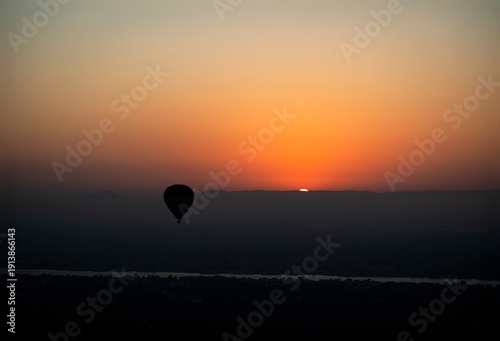 silueta de un globo aerostato con el sol saliendo por el horizonte en Luxor, Egipto