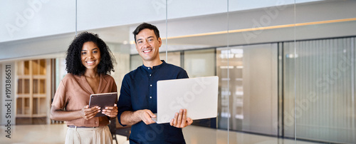 Canvas Print Young happy professional work team of two diverse confident female and male partners employees business people man and woman standing together in office looking at camera, corporate portrait