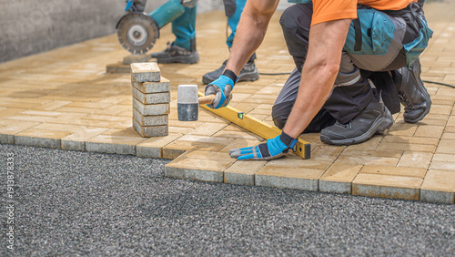 Laying of the interlocking paving. Worker compacting locking blocks in their laying bed using a rubber hammer.