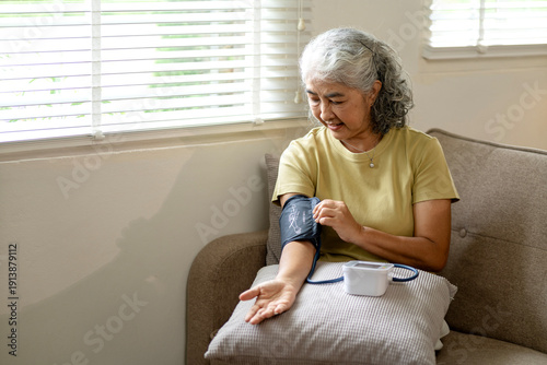 Senior Asian woman checking blood pressure home health monitoring chronic disease management elderly self care wellness