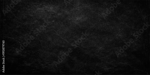 A dark and black grunge background featuring a rough vintage wall texture with a dirty grey paper pattern and blank chalkboard surface backdrop