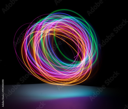 A long exposure photograph. Light painting photography, vibrant fairy lights in a circle shape against a black background
