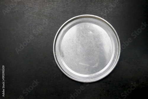 Aluminum tin plates on a dark table, flat lay view.