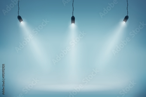 An empty theater stage is illuminated by a bright blue spotlight beam shining through the dark studio space to create an artistic backdrop design for a night show