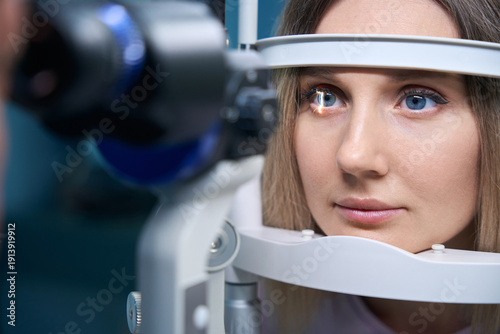 Obraz na plátně Young woman is diagnosed with eye pressure on special ophthalmological equipment