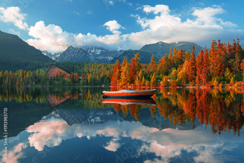 Štrbské Pleso (Strbske Pleso) in the High Tatras, Slovakia, with a panoramic view of a mountain lake surrounded by vibrant autumn foliage. Crystal clear water, dramatic sky, and majestic alpine peaks 