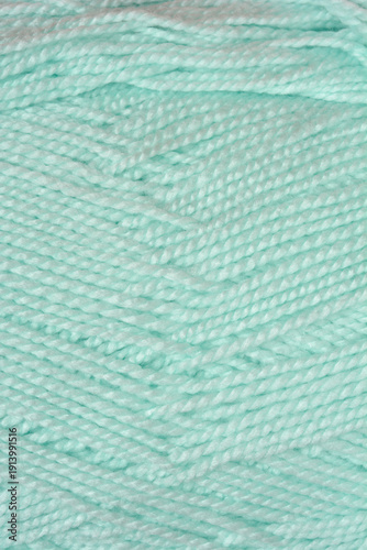 A macro shot showing the soft texture and twisted strands of light mint green wool yarn arranged in a diagonal pattern