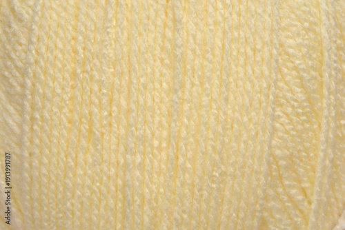 A detailed macro shot showing the soft vertical strands and twisted texture of pale yellow wool yarn