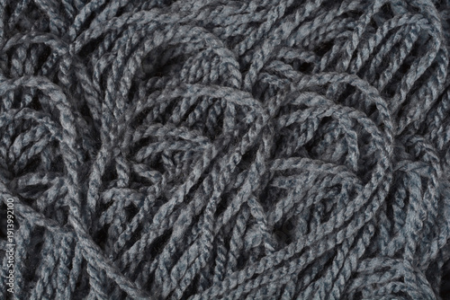 A macro close up shot of dark grey knitting wool yarn showing a complex tangled fiber texture