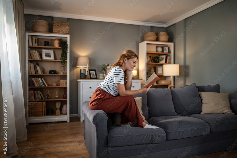 Obraz premium Woman reading book relaxing on sofa at home
