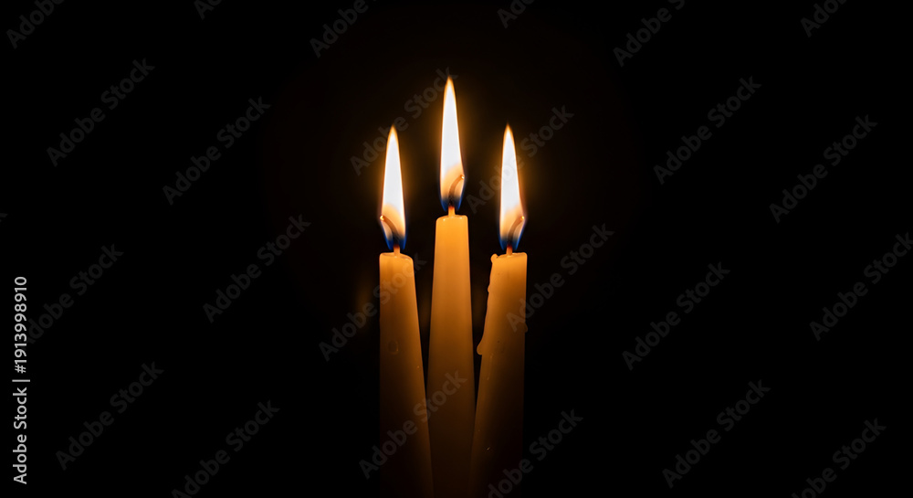 Fototapeta premium Intimate close-up of three cream tapered candles with golden flames on a black background, perfect for Valentine's Day, anniversaries, romantic evenings, home decor, spa ambiance,