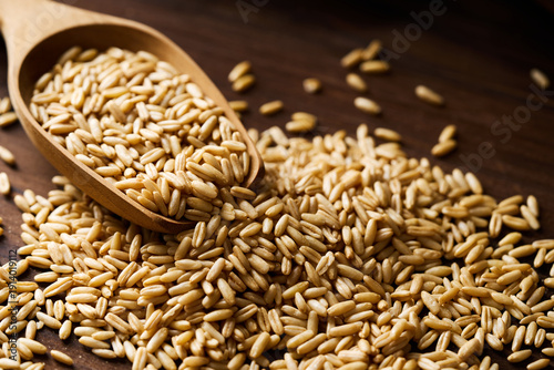 closeup whole oat groat in wood scoop on wooden rustic table dark mood background with copy space