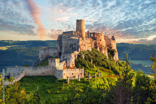 Spiš Castle (Spišský hrad) in Slovakia, a historic stone fortress perched on a hilltop, with panoramic views of the surrounding mountains. Dramatic sky, vibrant colors, and natural light highlight the