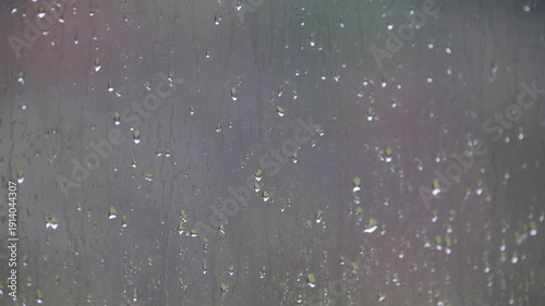Rainwater flowing down a glass window during a storm, with a blurred background creating a sad mood