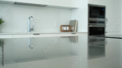 Hand wiping a modern kitchen counter with a white cloth