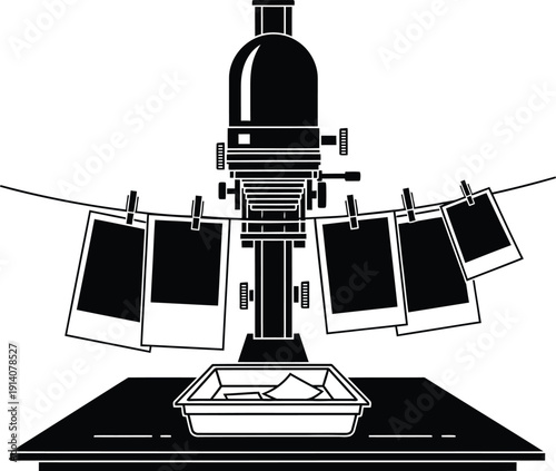 Vintage darkroom photo enlarger with hanging prints on rope and developing tray for photography.