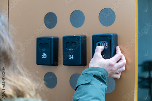 Foto Close up of hand adjusting numeric combination on outdoor key safe installed for short term rental self check in system