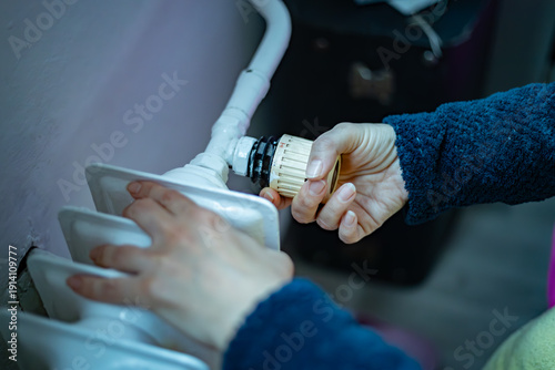 Bare hands search for warmth on a cold radiator during a power outage and energy crisis.