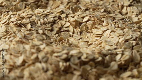 Dry oat flakes background, close up, rotation. Uncooked raw oat flakes grains. Healthy breakfast and diet eating ingredients for making oatmeal porridge. Gastronomy concept, organic food