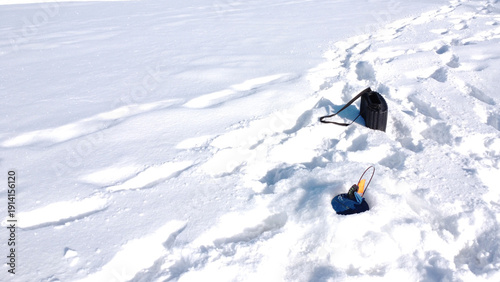 Close-up of an ice fishing tip-up with an orange flag in the snow