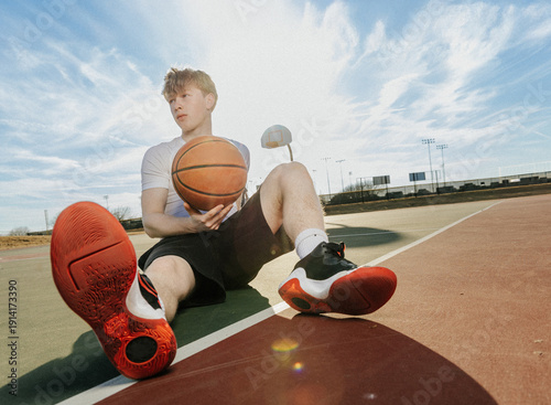 Young Man Holding a Basketball on an Outdoor Court