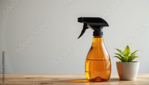 Orange Cleaning Spray Bottle on Wooden Table with Green Plant in Small White Pot Against Neutral Background