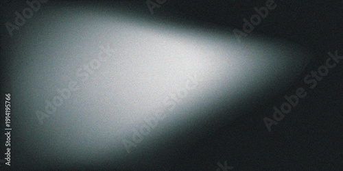 A bright spotlight shines on a brushed silver stainless steel plate with a metallic texture, creating a shiny aluminum stage backdrop and gray industrial wall pattern