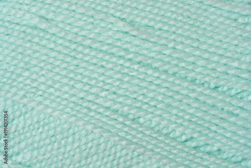 Macro close up shot of a soft light blue mint colored knitting yarn with a twisted fiber texture
