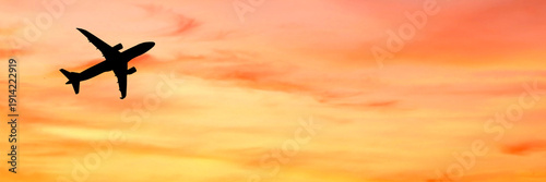 An airplane silhouette soaring through a vibrant sunset sky, creating a beautiful contrast