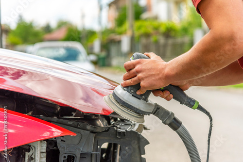 Repairing car body by puttying close up work after the accident by working sanding primer before painting. , The mechanic repair the car.