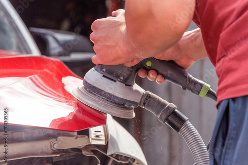 Repairing car body by puttying close up work after the accident by working sanding primer before painting. , The mechanic repair the car.