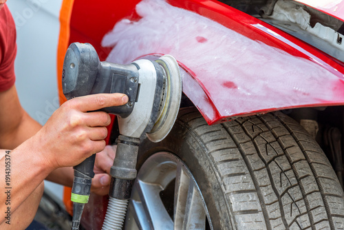 Repairing car body by puttying close up work after the accident by working sanding primer before painting. , The mechanic repair the car.