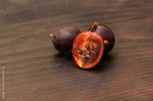 Half of a juicy gooseberry on a dark wooden board