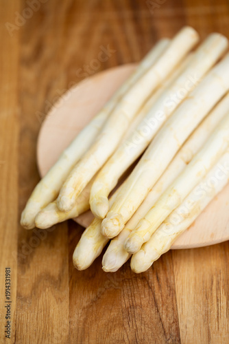Fresh white asparagus on wooden board, seasonal healthy vegetable.
